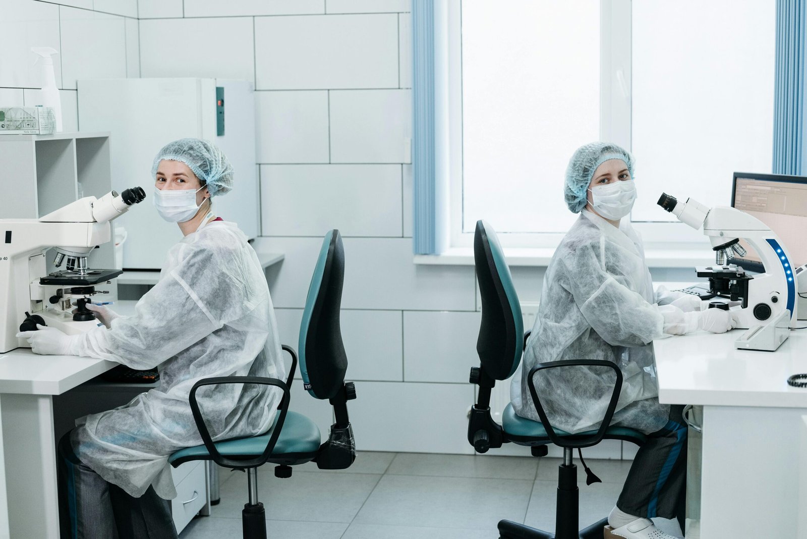 Two female scientists working with microscopes in a laboratory setting.